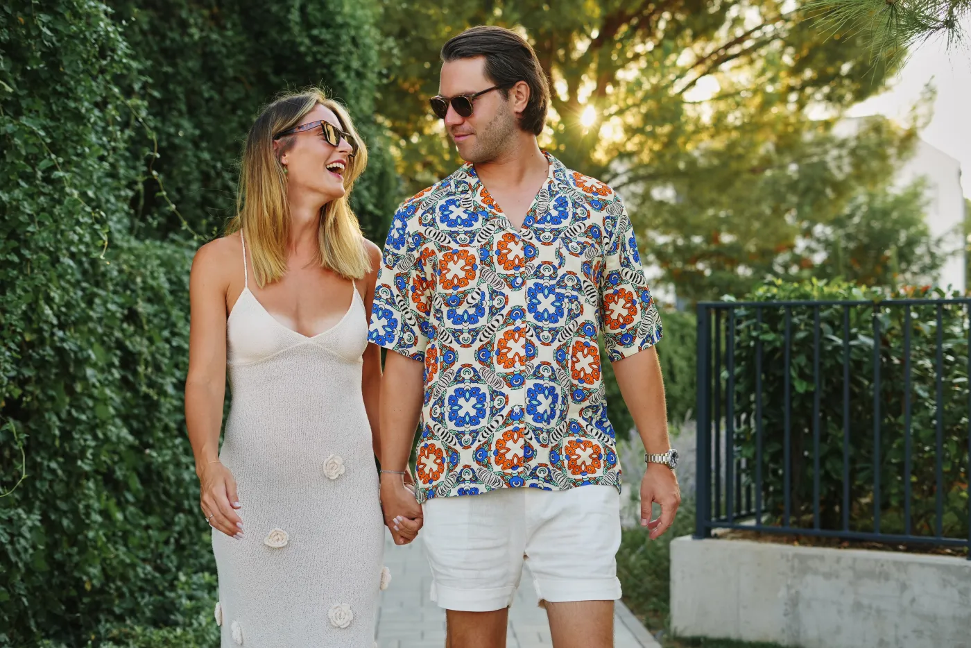 A couple holding hands and laughing as they look at each other during their photo session